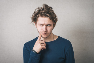 Man thinks finger to his mouth. Gray background