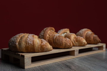 Colazione cornetti con un background rosso serviti su un piatto di legno