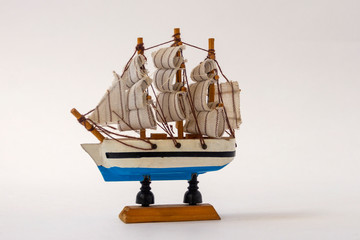 Small toy ship with sails on a white background. Wooden model of a boat. The concept of summer,...