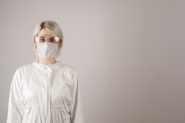 A girl in a protective suit and mask and glasses to protect health from viral, epidemic and...