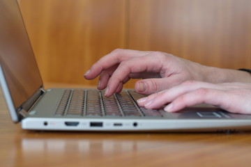 Closeup shot of hands typing on laptop keyboard