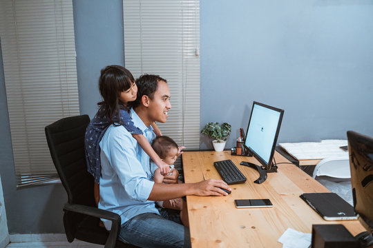 asian businessman working from home while babysitting. parent with child working at home