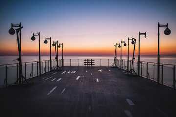 Sunset Colors And Amazing Seaside Horizon View From The Pier. Colorful Sunset And Outdoor Lams At Evening.