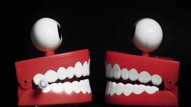  two toy teeth gossiping with black background 