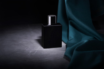 Packaging profumo su uno sfondo di nero, un piano di marmo e un tessuto verde, foto pubblicità moda