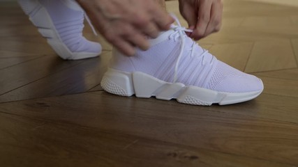 Close up of sporty senior man tying shoelaces on sneaker. Home workout. - Powered by Adobe