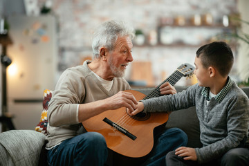 Grandpa and grandson playing guitar. Grandfather and grandson enjoying at home.	