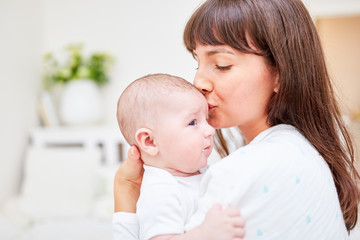 Fototapeta na wymiar Mutter gibt Baby Kuss auf die Stirn