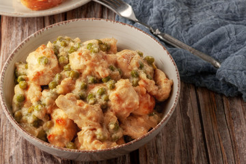 Braised chicken fillet with green peas on a wooden table