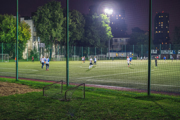 
football players play on the field at night under spotlights