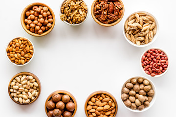 Fototapeta premium Nuts set in bowls on white background top-down frame copy space