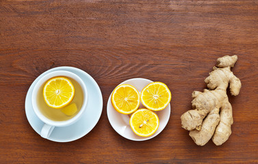 A cup of hot herbal green tea with lemon and spicy ginger on wooden table. Useful healing drink with high temperature, coronavirus infection, colds and flu. Flat lay, copy space, top view, close-up