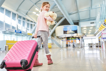 Alleinreisendes Kind mit Koffer im Flughafen Terminal