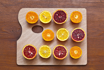 Top view of multi-colored appetizing halves of juicy fresh citruses on wooden cutting board in the form of an art palette. Vitamin C-rich fruits are good for coronavirus infection. Flat lat, close-up