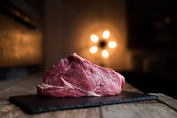 Taglio di carne di manzo su piatto di ardesia, tavolo in legno e background con luce calda