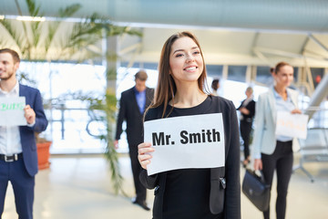 Geschäftsfrau mit Namensschild am Flughafen