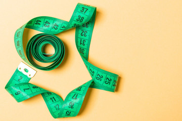 Top view of measure tape curtailed into a spiral with copy space. Concept of sewing accessory or healthy diet on orange background
