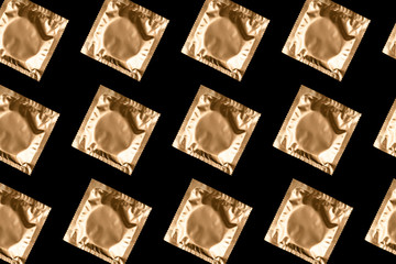 Pattern made from golden condoms on black background