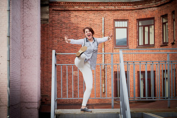 Brunette funny pretty girl on roof in Central part of old city. Walk in downtown. Portrait of a girl on the street