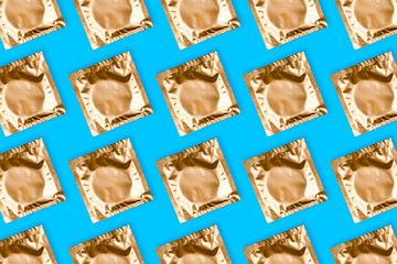 Pattern made from golden condoms on blue background
