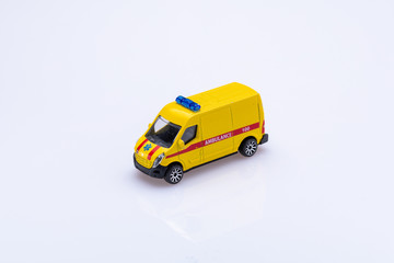 Yellow metal ambulance toy isolated in front a white background