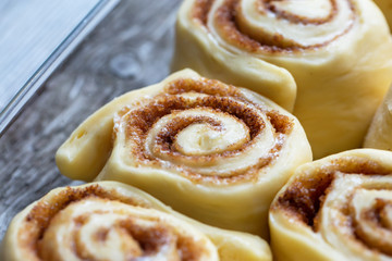 Raw homemade cinnamon buns on wooden table, bevor baking, dark background, copy space, top view.