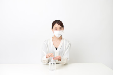 マスクをしながら手を消毒する女性