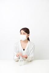 マスクをしながら手を消毒する女性