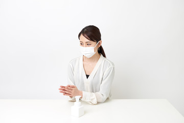 マスクをしながら手を消毒する女性