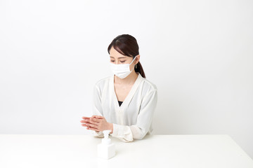 マスクをしながら手を消毒する女性
