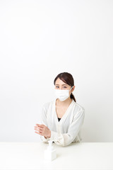 マスクをしながら手を消毒する女性