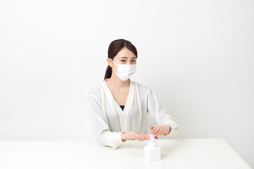 マスクをしながら手を消毒する女性