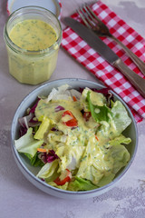 vegetarian food. salad of cabbage tomato on a light white plate on a grey background with yoghurt and mustard herbal dressing. healthy food