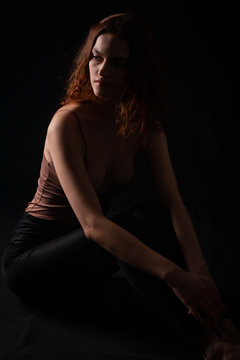 Portrait of a young curly girl in a dark studio