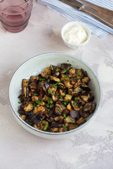 Plate of fried diced eggplants and creme fraiche on grey background. Ready to eat.