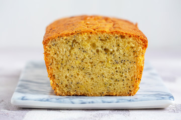 Lemon & Poppy Seed Pound Cake on marbled plate on grey table.