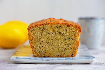 Lemon & Poppy Seed Pound Cake on marbled plate on grey table.