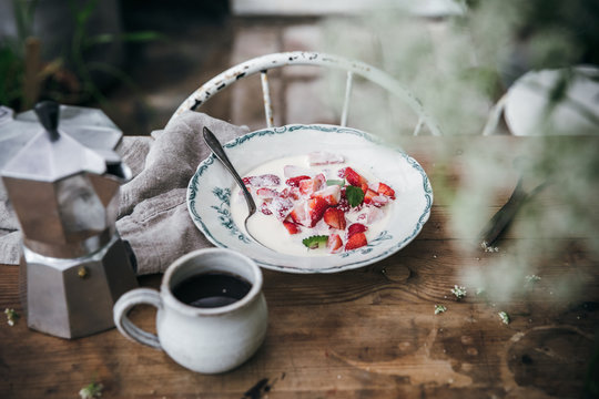 Strawberries & milk with a cup of coffeee on an old wooden table