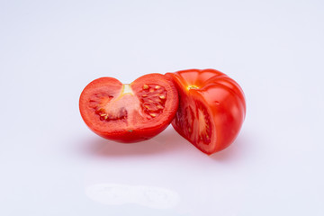 Red tomatoes sliced in half in front of a white background