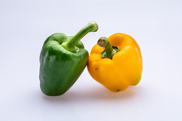 green and yellow peppers isolated in front of a white background
