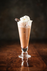delicious cold chocolate ice cream milkshake with cookie in a long glass, dark wooden background, side view, vertical