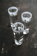 Tequila shots on the dark rustic background. Selective focus. Shallow depth of field.
