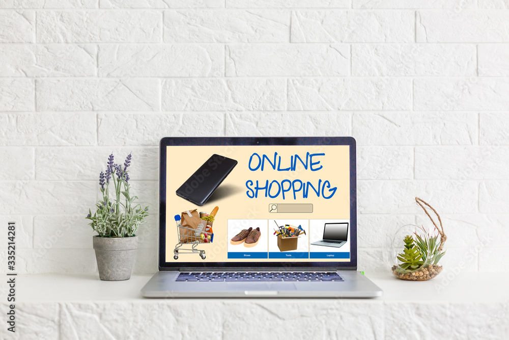 Poster laptop with onlain shopping site on the screen stands on the table in the office with phone and watc