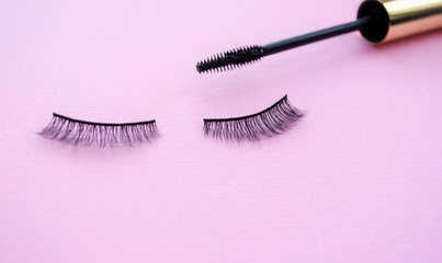 false eyelashes and black mascara on a purple background. Make up concept. Mascara or false lashes?