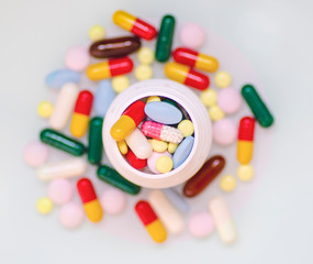 Bottle of multicolored pills with tablets on a gray background