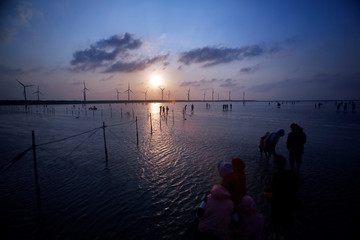 The sunset scenery by the sea, against the wind turbines in the distance, this beach is peaceful...