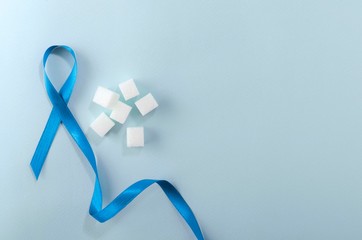 Top view of blue ribbon as a sign of diabetes disease, sugar on the blue surface.Empty space for...