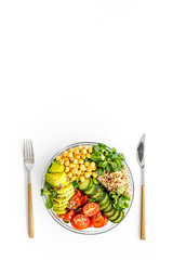 Veggie bowl. Vegetable salad with quinoa, avocado, tomato, spinach and chickpeas - on white table. Top view copy space