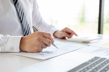A business man is sitting at a desk and calculating financial graphs about real estate investment expenditures