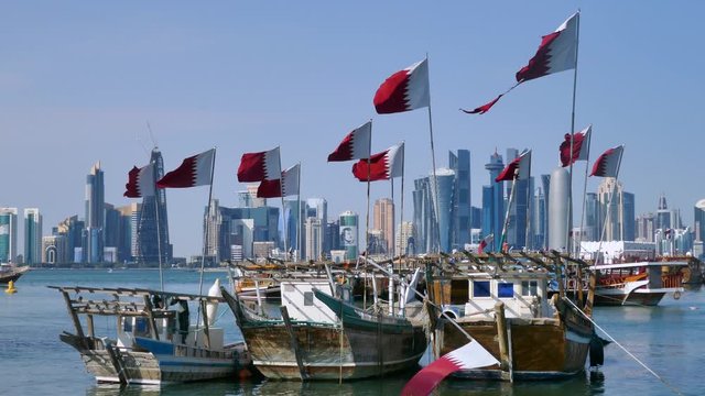 Traditional Dhow, Arab sailing vessels with Qatar flags in the harbour with the Doha skyline in the background